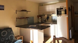 A compact kitchen with a central island, built-in appliances, and a wooden ceiling. - 1st floor, tv, ski locker, 58m², Villard de Lans (Corrençon-en-Vercors)