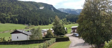 Ein ländliches Anwesen mit einem Schotterweg, der zu einem weißen Gebäude führt, umgeben von grünen Feldern und Bäumen.