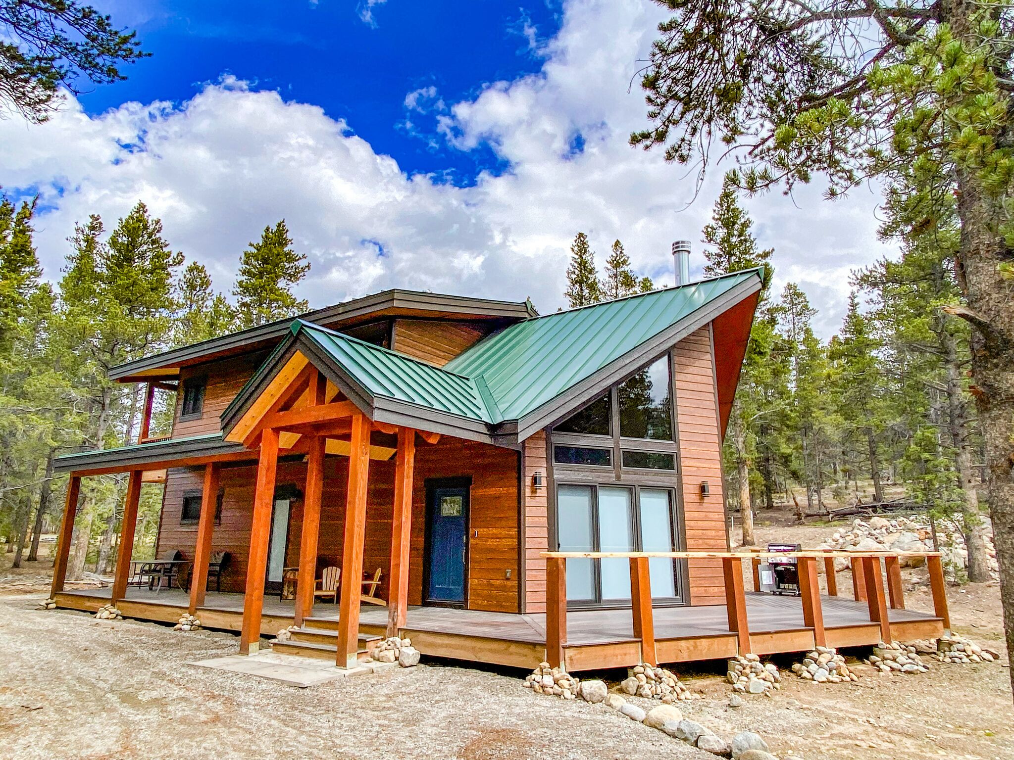 A cabin with a wooden exterior, a green roof, and a deck.