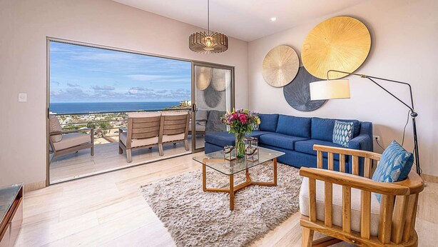 A modern living room with a sofa, coffee table, and a view of the ocean. - Punta Serena | Los Tules Oceanview Penthouse Condo (Residencial Los Tules)