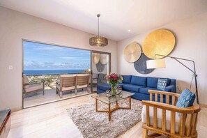 A modern living room with a sofa, coffee table, and a view of the ocean.
