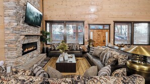 Ein gemütliches Wohnzimmer mit Kamin aus Stein, bequemen Sofas und einem großen Wandfernseher.