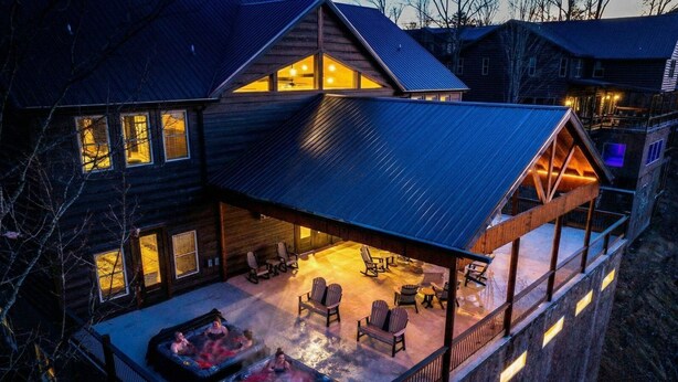Ein mehrstöckiges Blockhaus mit überdachter Terrasse, Whirlpools und Sitzgelegenheiten im Freien.