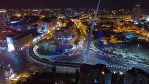Un paisaje urbano nocturno con un puente destacado y edificios iluminados.