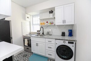 Kitchen features an oven, sink, coffee maker, and washing machine.