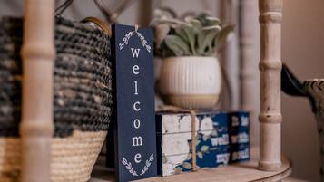 A wooden shelf with a woven basket, a welcome sign, and a potted plant.