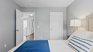 A bedroom with a bed, a nightstand, a lamp, and a door leading to another room.