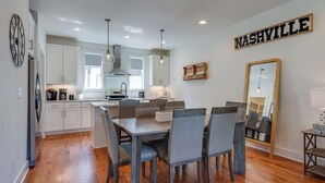 A modern kitchen with white cabinets, a dining area with a table and chairs, and a large mirror on the wall.