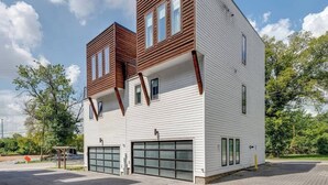 A two-story building with a white exterior and brown wooden accents, featuring two garage doors and a covered entryway.