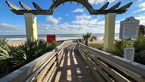 A wooden boardwalk leading to a beach with a clear sky.