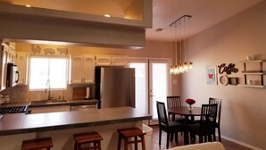 Cocina moderna con una isla central, comedor con sillas y decoración temática de café.