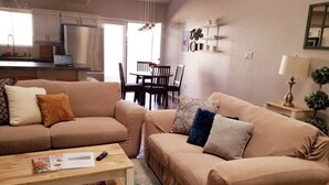 Una sala de estar con un sofá color beige, una mesa de centro de madera y un comedor con mesa y sillas.