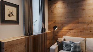 Un salon moderne avec un mur d’accent en bois, une œuvre d’art représentant une tête de cerf encadrée, une fenêtre avec des rideaux et un canapé agrémenté de coussins à carreaux.
