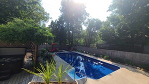 Un patio trasero con piscina, rodeado de árboles y una valla de madera.