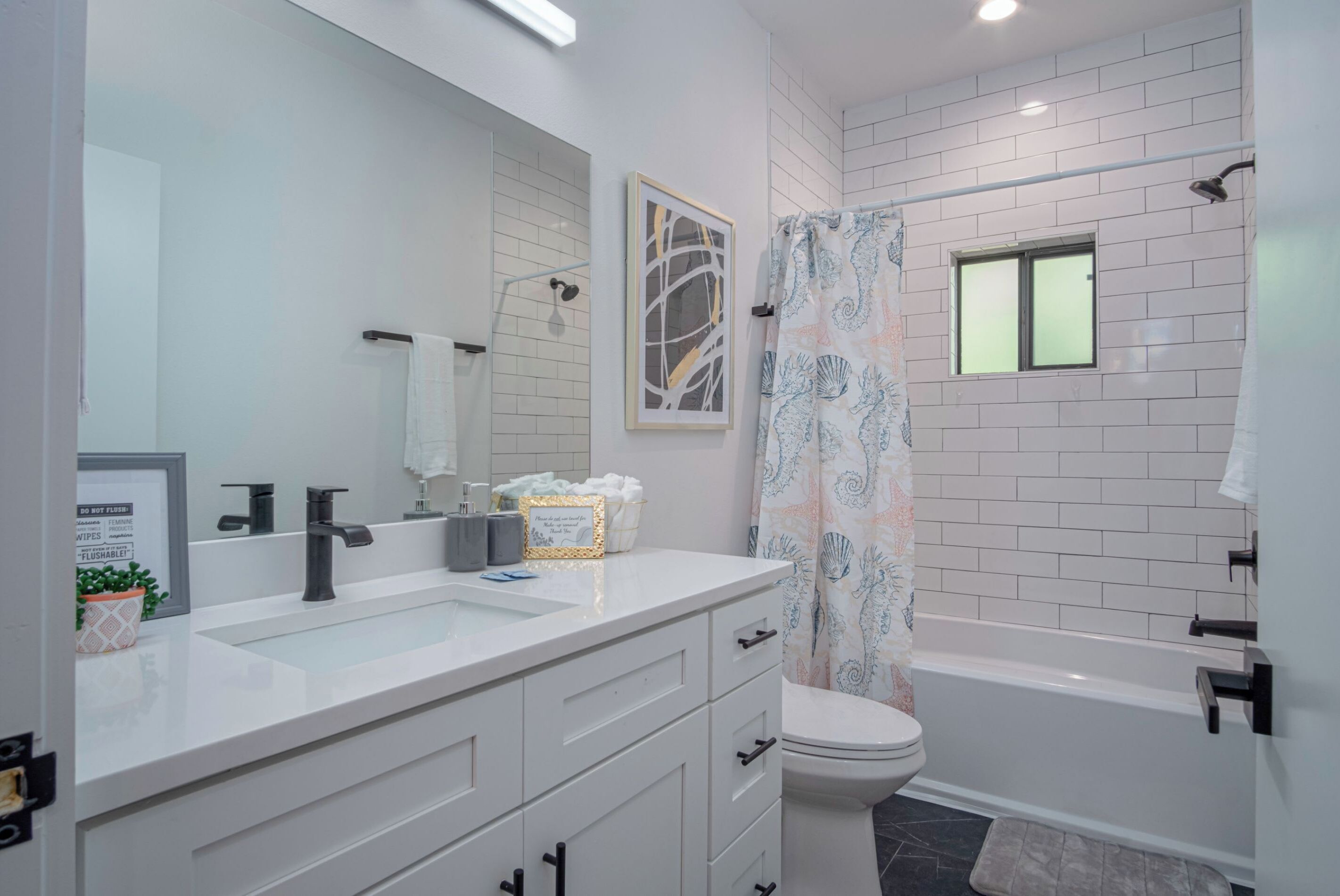 A modern bathroom with a white vanity, a toilet, and a bathtub.