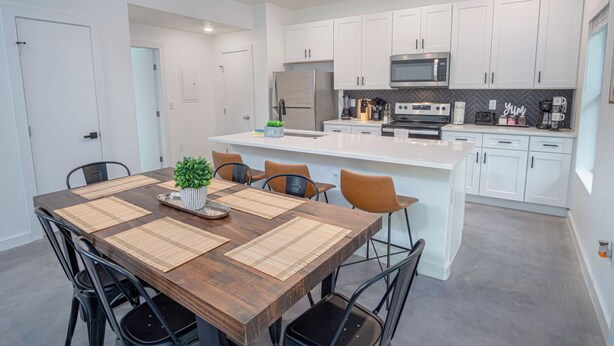 Una cocina moderna con armarios blancos, electrodomésticos de acero inoxidable y una isla central.