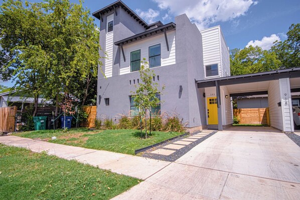 Stylish two-story home with a clean design, featuring a covered driveway and a well-manicured lawn.