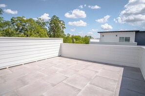 Enjoy panoramic views from this rooftop terrace with a clean design, paved tiles, and a white railing.