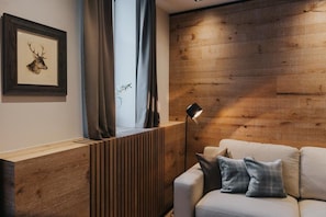 Un soggiorno moderno con una parete decorata in legno, un'opera d'arte raffigurante un cervo impagliato, un divano con cuscini a quadri e una lampada da terra.