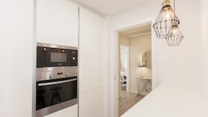 A modern kitchen with built-in appliances, a white interior, and a stylish pendant light. - FLH Marquês Pombal Flat with Balcony (Lisbon)