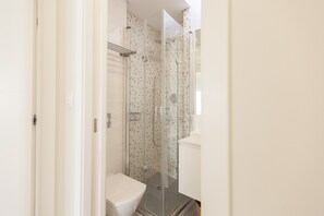 Ein modernes Badezimmer mit einer einteiligen Duschkabine, einer weißen Toilette und einem weißen Waschbecken.