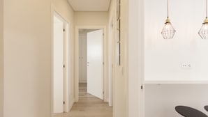 A hallway with a wooden floor, white walls, and a door leading to another room. - FLH Marquês Pombal Flat with Balcony (Lisbon)