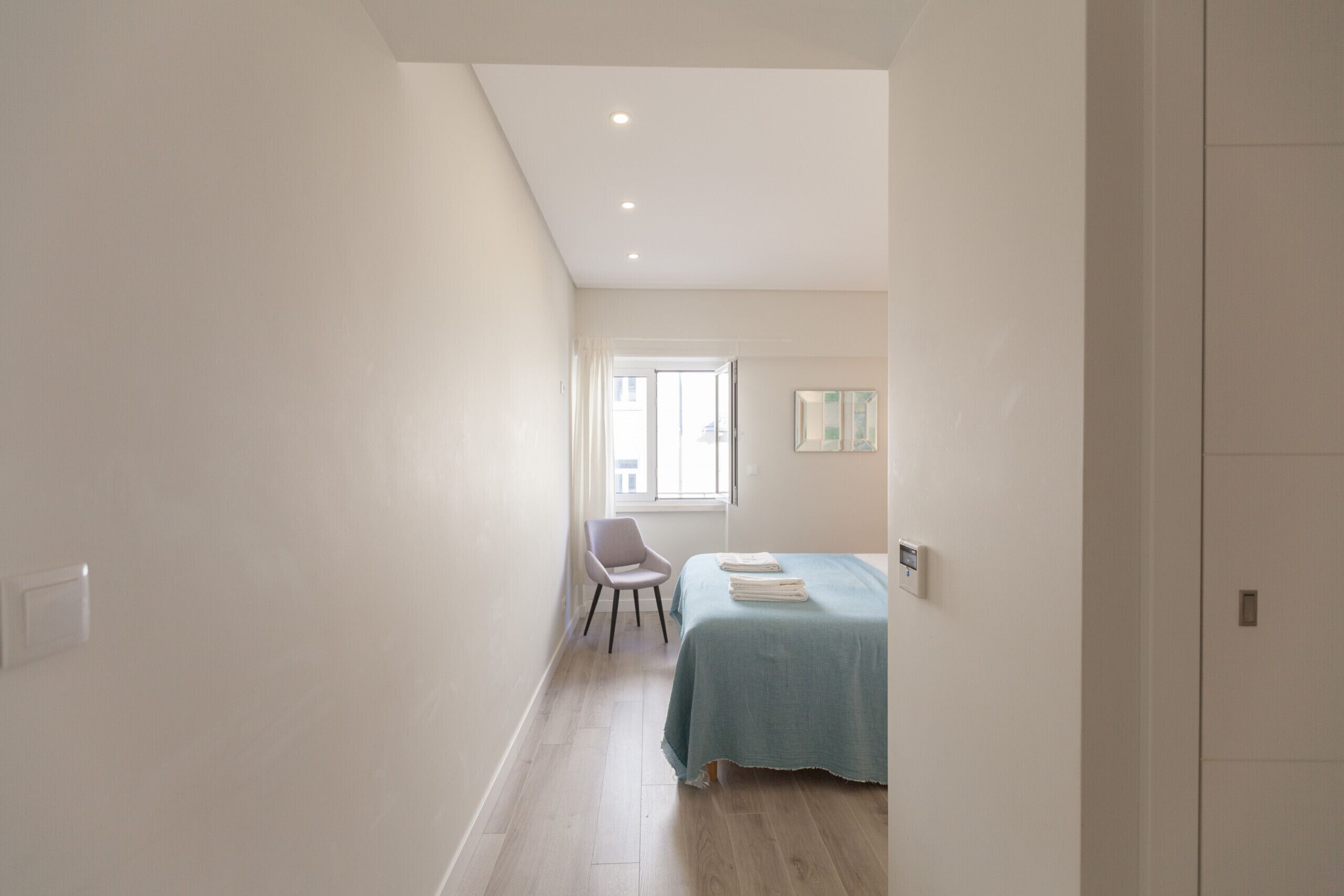 A bedroom with a bed, a chair, and a window.
