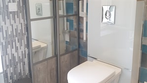 A bathroom with a modern design, featuring a toilet, a bidet, and a shower area with glass doors.