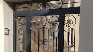 A black metal gate with intricate designs, attached to a beige wall.