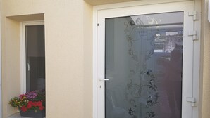 A white door with a decorative glass panel and a small window with a flower box.