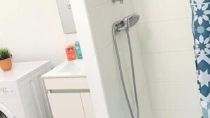 A bathroom with a shower, a washing machine, and a small sink. - Agréable F2 Proche Gare (Le Mans)