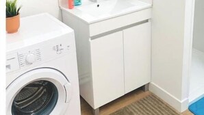 A compact bathroom with a washing machine, a sink, and a mirror. - Agréable F2 Proche Gare (Le Mans)