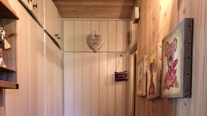 A narrow hallway with wooden walls, a tiled floor, and a door with a striped rug.