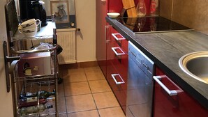 A compact kitchen with red cabinets, a stainless steel sink, and a coffee machine.