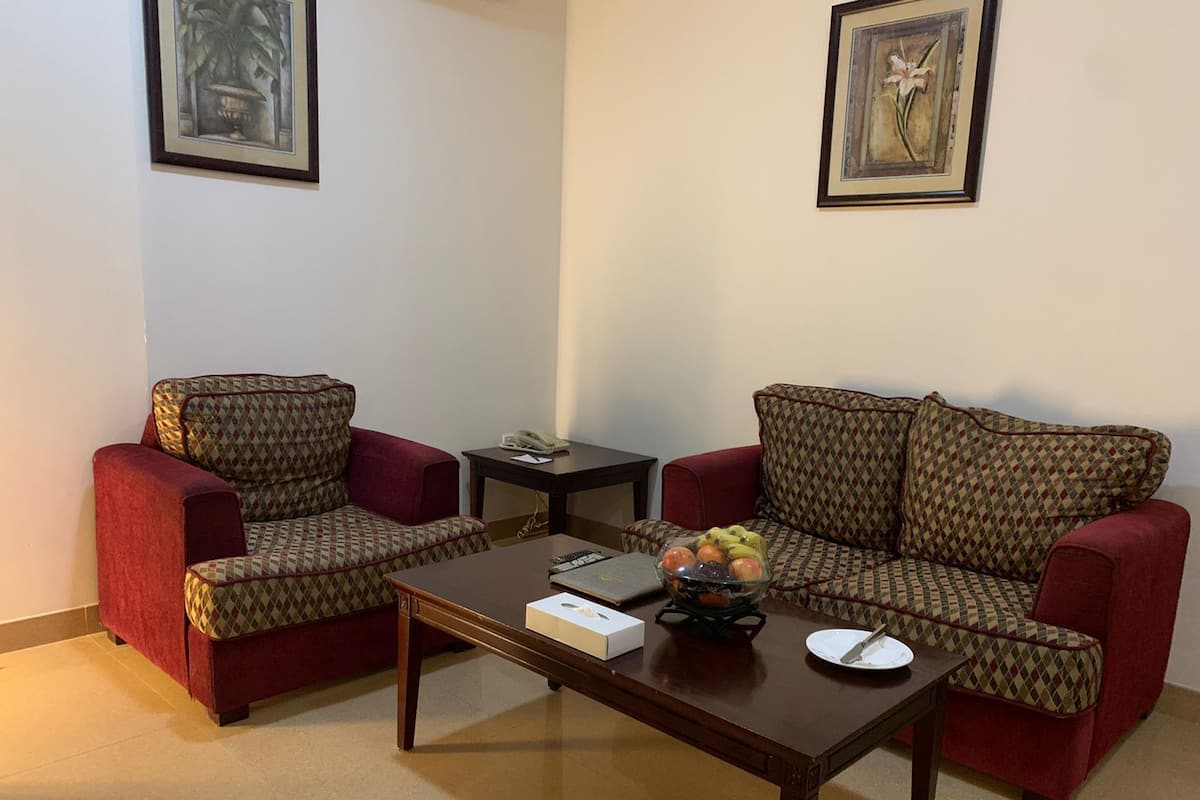 A living room with two patterned armchairs, a wooden coffee table, and a small side table with a telephone.