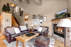 A living room with a fireplace, leather sofas, a wooden coffee table, and framed pictures on the wall.