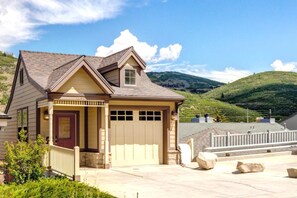 A single-story house with a garage, a front porch, and a view of a hilly landscape.