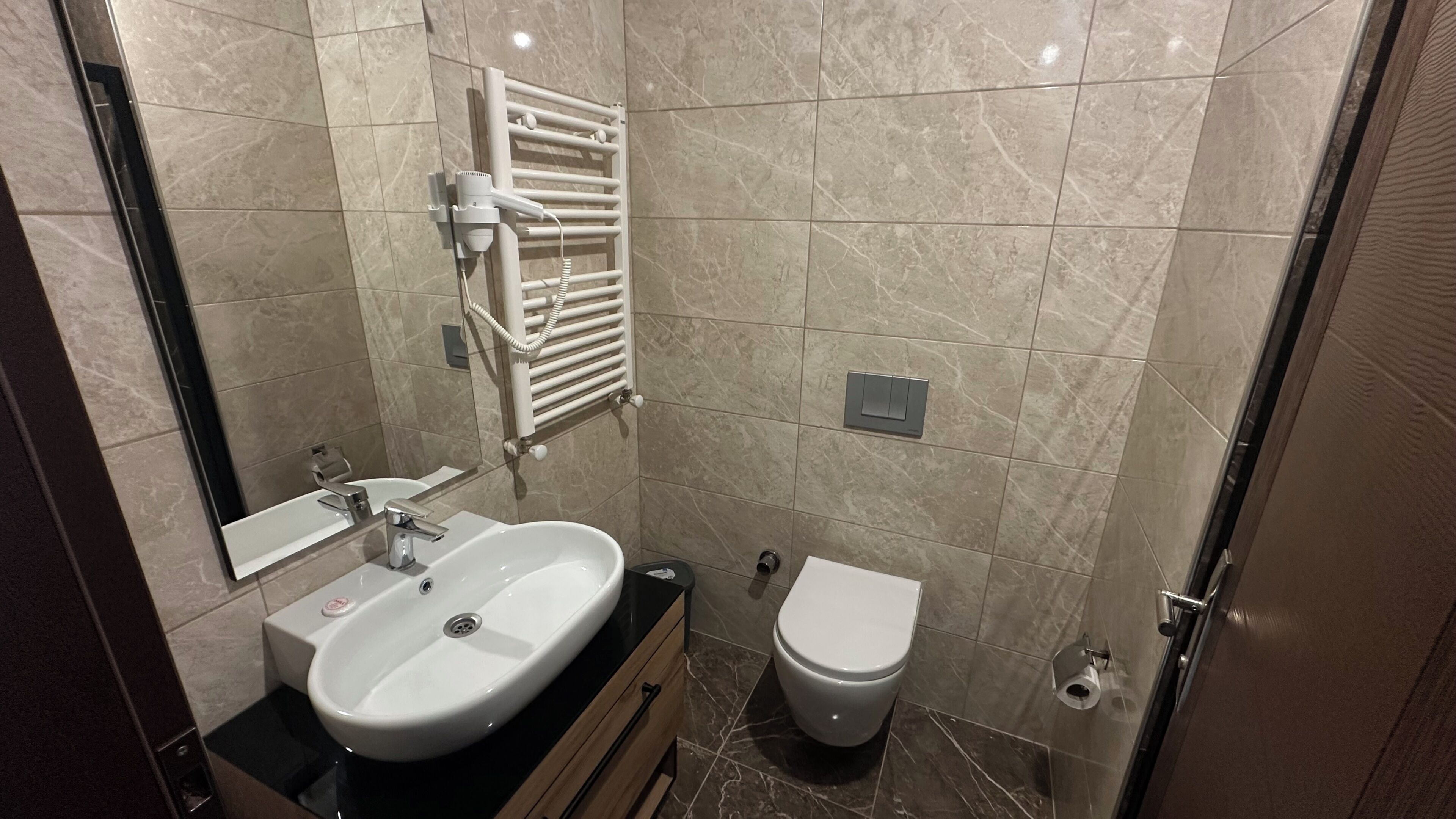 A bathroom with a sink, mirror, towel rack, toilet, and a shower area.