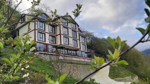Un immeuble à plusieurs étages, avec une base en pierre, un balcon doté d’une balustrade et une enseigne indiquant qu’il s’agit d’un hôtel.