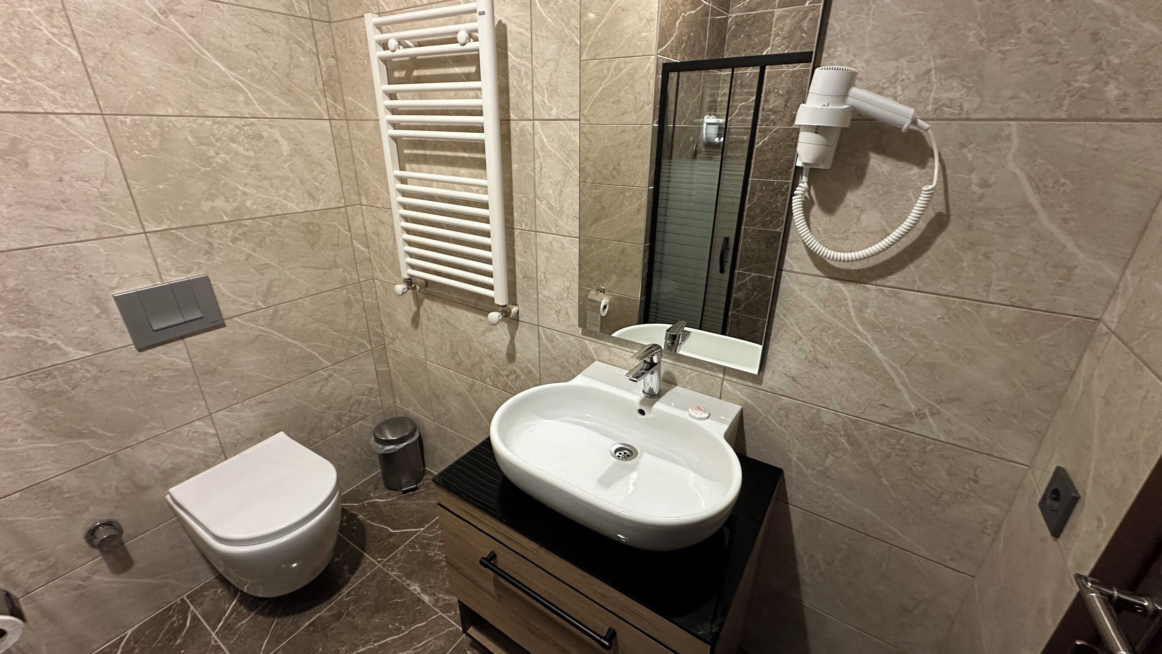 A bathroom with a white toilet, a sink with a mirror, a towel rack, and a hairdryer.