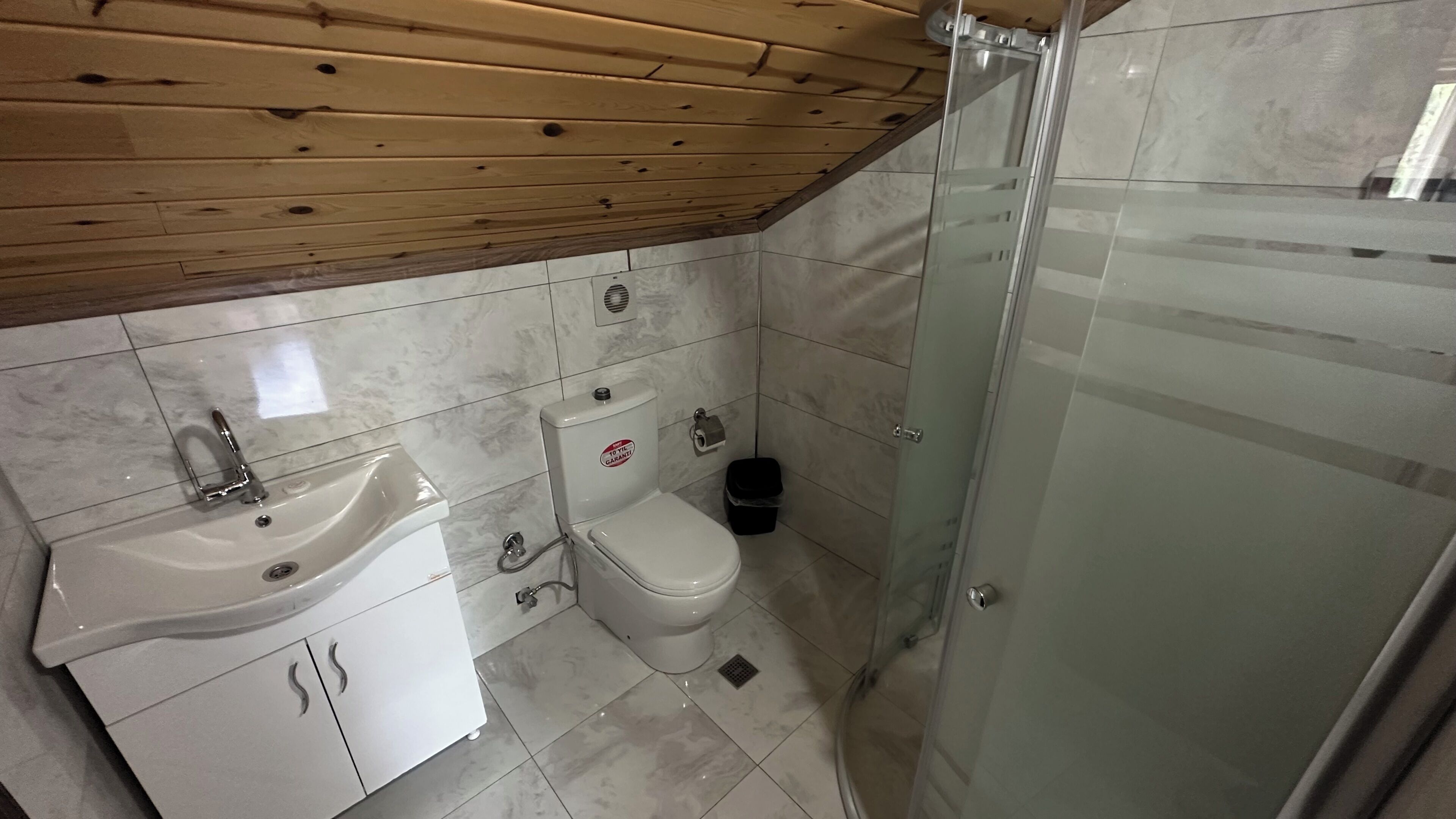 A bathroom with a sink, toilet, and glass shower enclosure.