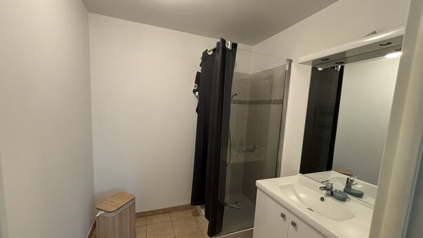 A bathroom with a shower, a sink, and a mirror.