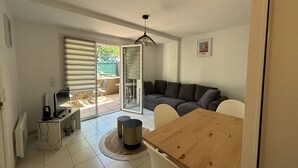 A living room with a wooden dining table, a sofa, and a TV.