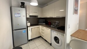 Une cuisine compacte équipée d’un réfrigérateur, d’un four à micro-ondes, d’un grille-pain, d’un évier et d’un lave-linge.