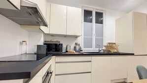 A modern kitchen with white cabinets, a black countertop, a microwave, a toaster, and a sink. - N&J - LE PIERLAS - Place Garibaldi - Very close Old Town (Niza)