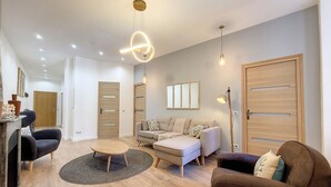 A modern living room with a sofa, armchairs, a coffee table, and a floor lamp. There are wooden doors and a mirror on the wall. - N&J - LE PIERLAS - Place Garibaldi - Very close Old Town (Niza)
