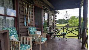 A wooden deck with outdoor furniture, a view of a golf course, and a rustic cabin structure. - Sweet Serenity where peace is a necessity! (Franklin)