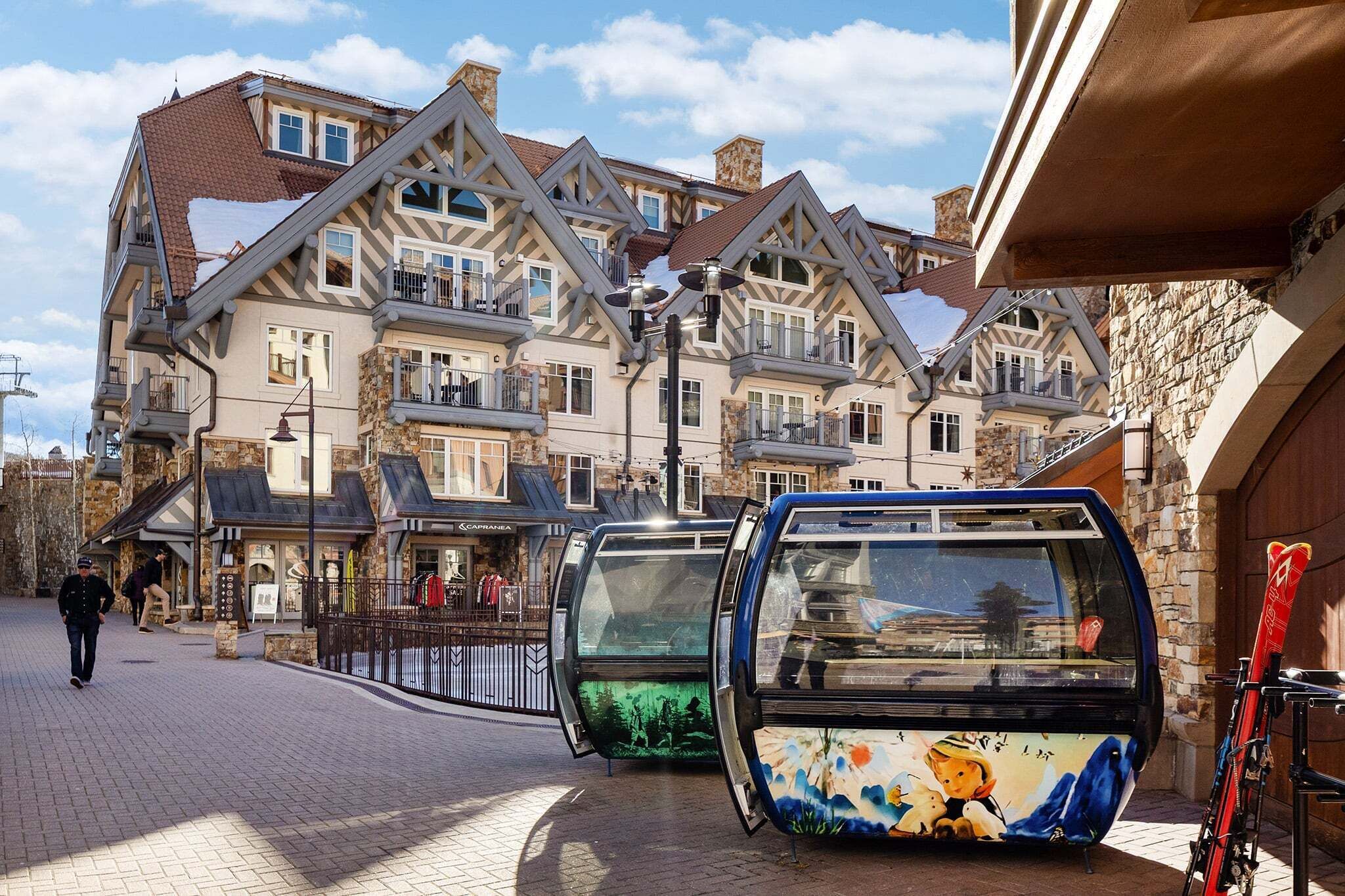 Un edificio de estilo europeo tradicional, con techo a dos aguas pronunciado, fachada de piedra y una estación de teleférico de diseño colorido.