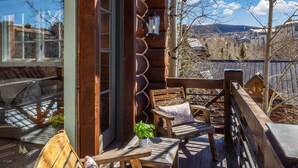 Une terrasse en bois avec des sièges extérieurs, une vue sur la ville et une montagne en arrière-plan.