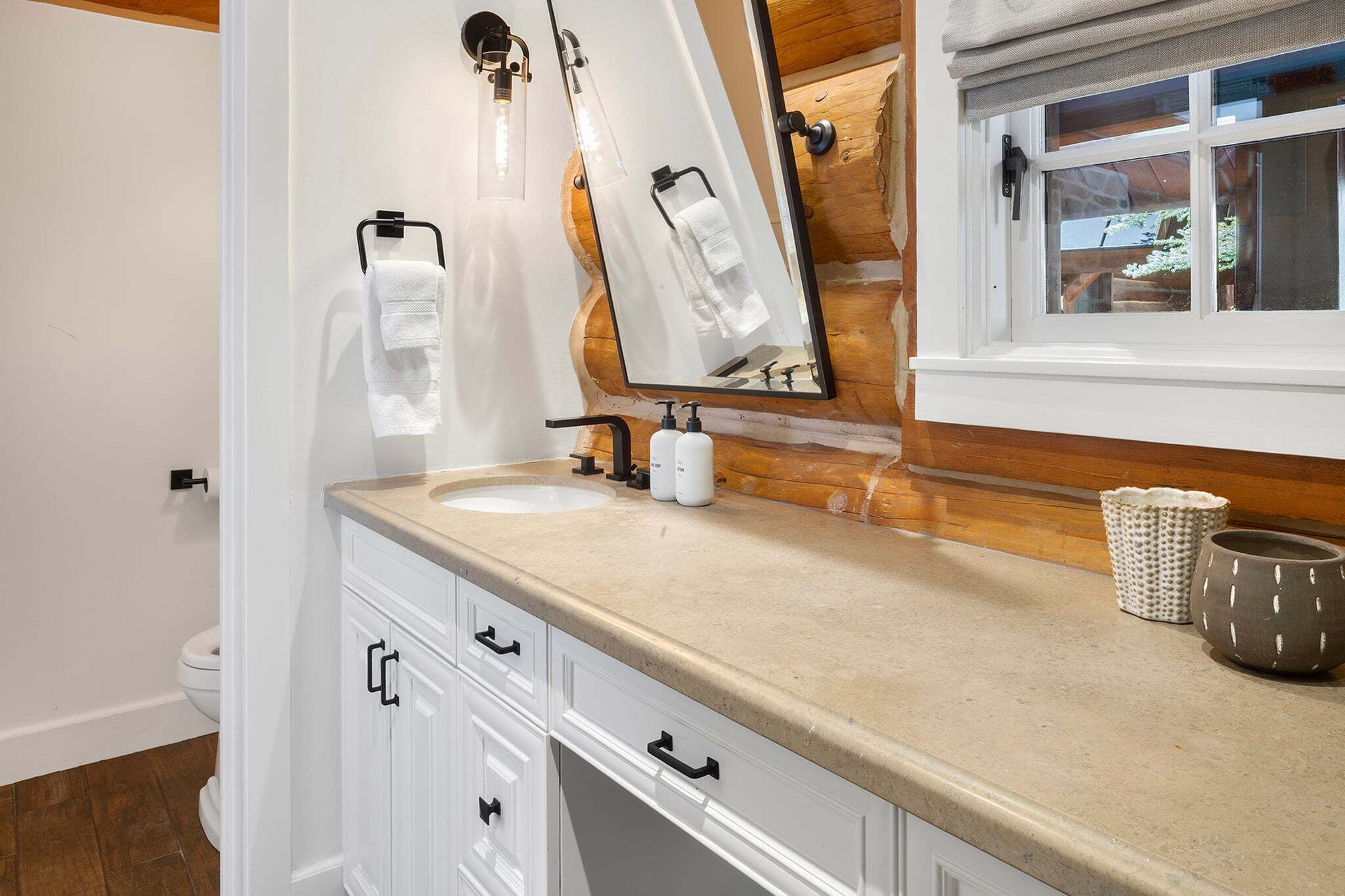 Un baño con pared de madera, un espejo grande, un lavamanos y una ventana.